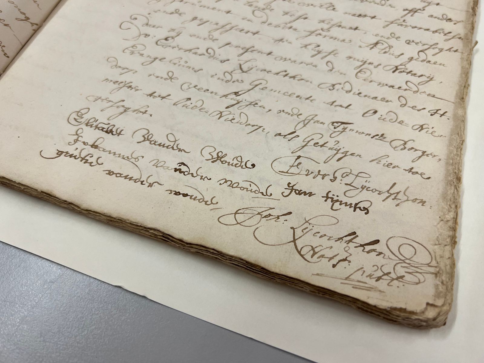 Handgeschreven historisch document met cursiefschrift op vergeeld papier met zichtbare vouwlijn.