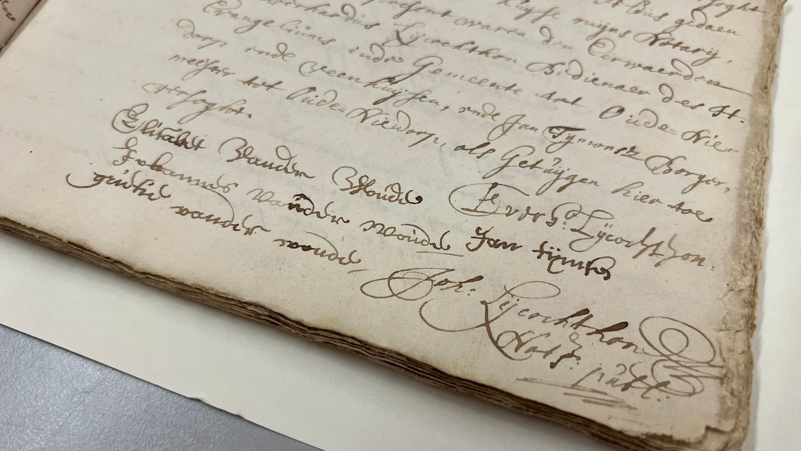 Handgeschreven historisch document met cursiefschrift en handtekening op vergeld papier.