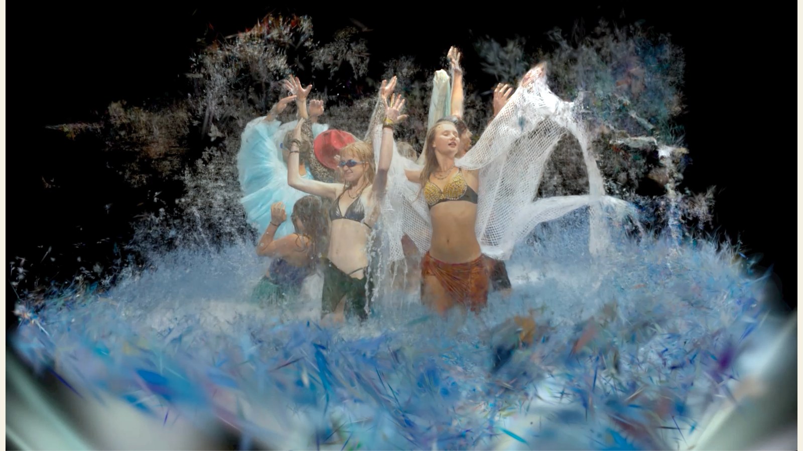 Groep mensen in zomerkleding spelen in schuimend water met witte doeken, tegen donkere achtergrond.